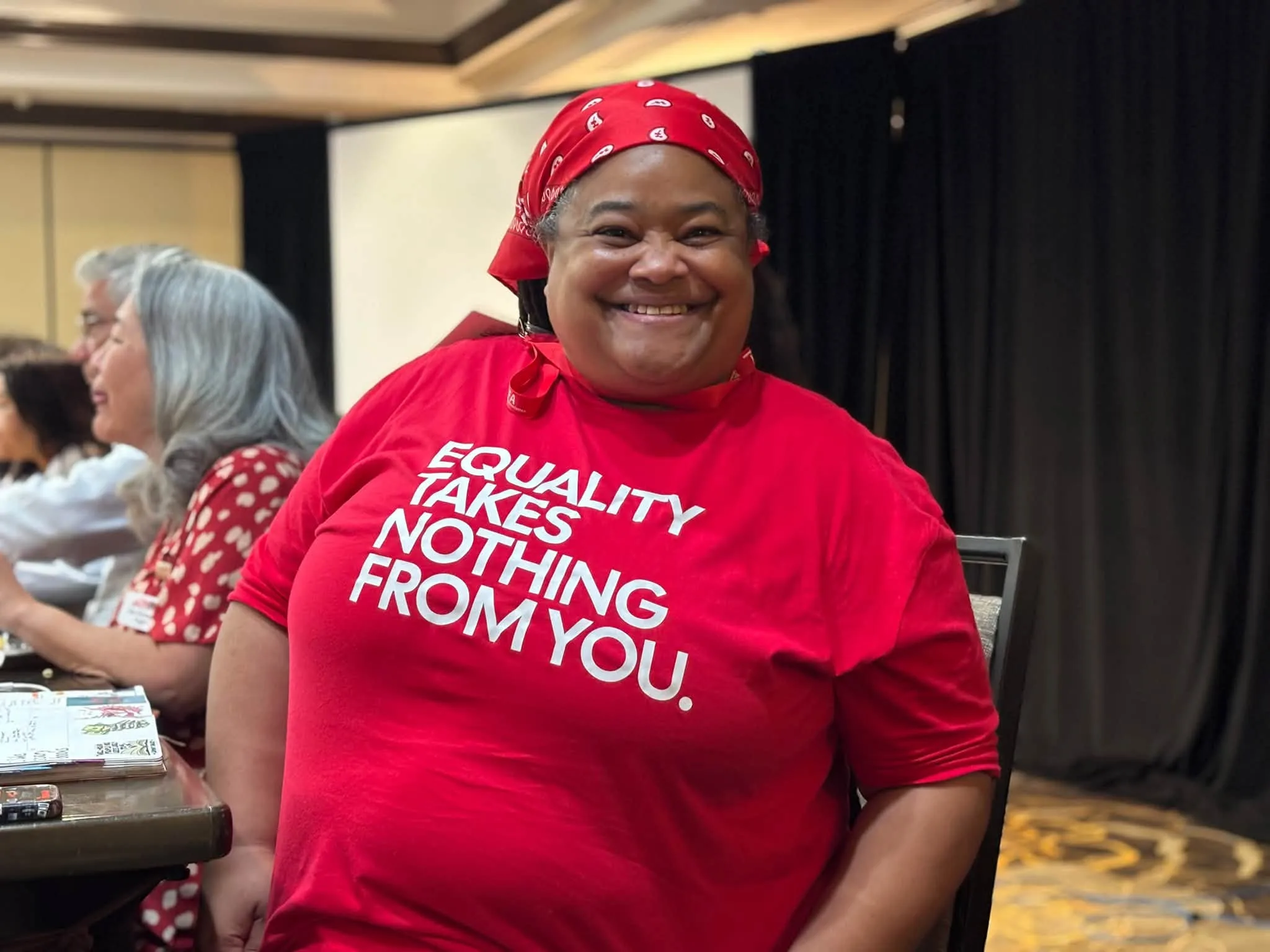 A woman wearing a red shirt that says "Equality takes nothing from you."