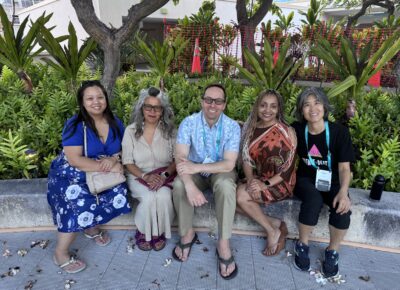 A group of counselors sit down together outside.